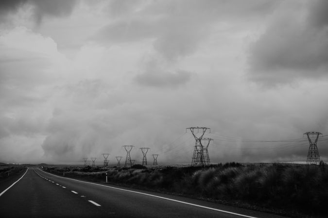 Empty road and electric poles under stormy sky