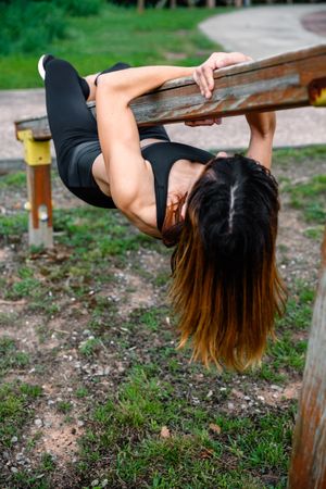 Sportswoman training hanging on a wooden bar