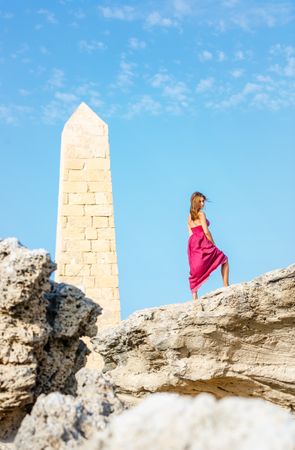 Woman in dress standing near stone monument