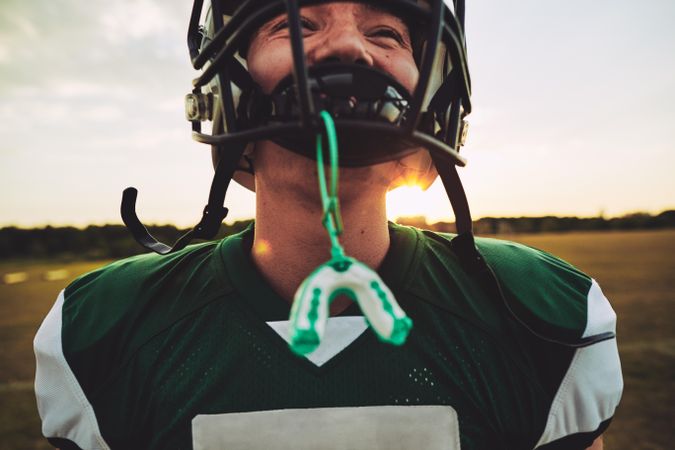 Smiling man in football helmet with mouthguard attached