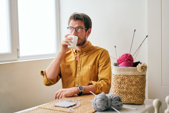 Man drinking hot tea during knitting