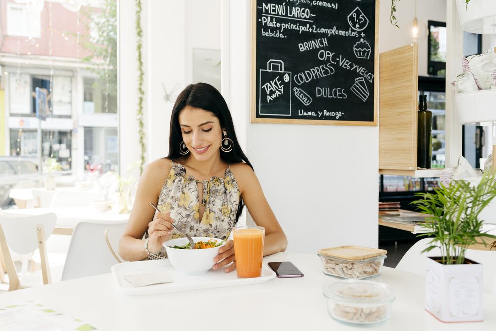 Cheerful woman with healthy food in cafe