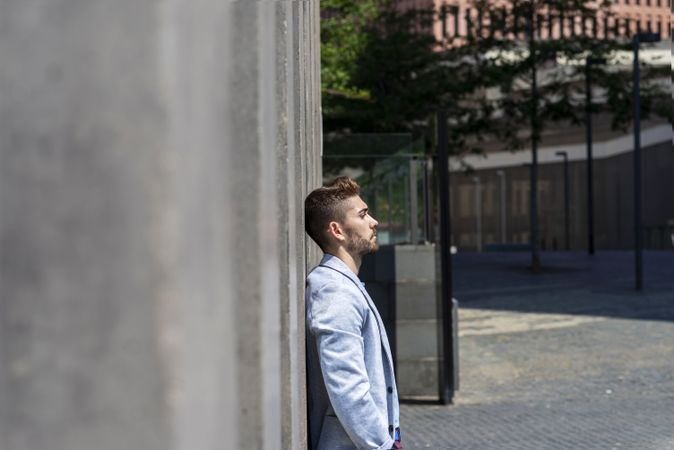 Side view of man leaning on wall outside