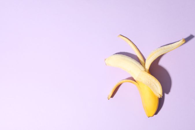 Opened banana on violet background. Fresh fruit