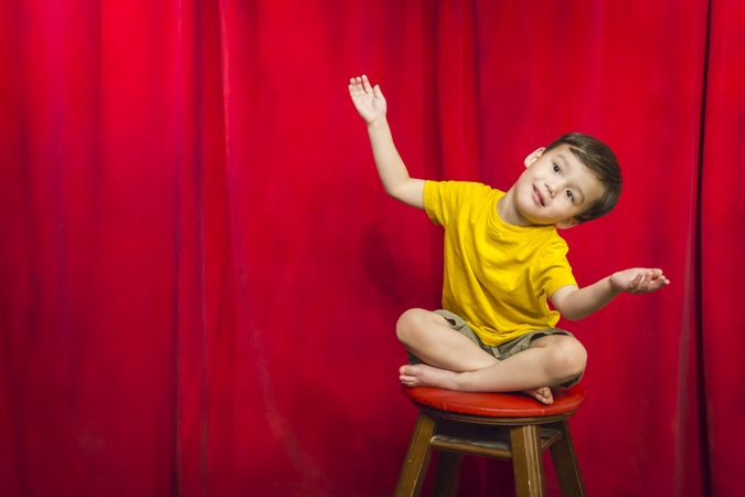 Biracial Boy Sitting on Stool in Front of Curtain