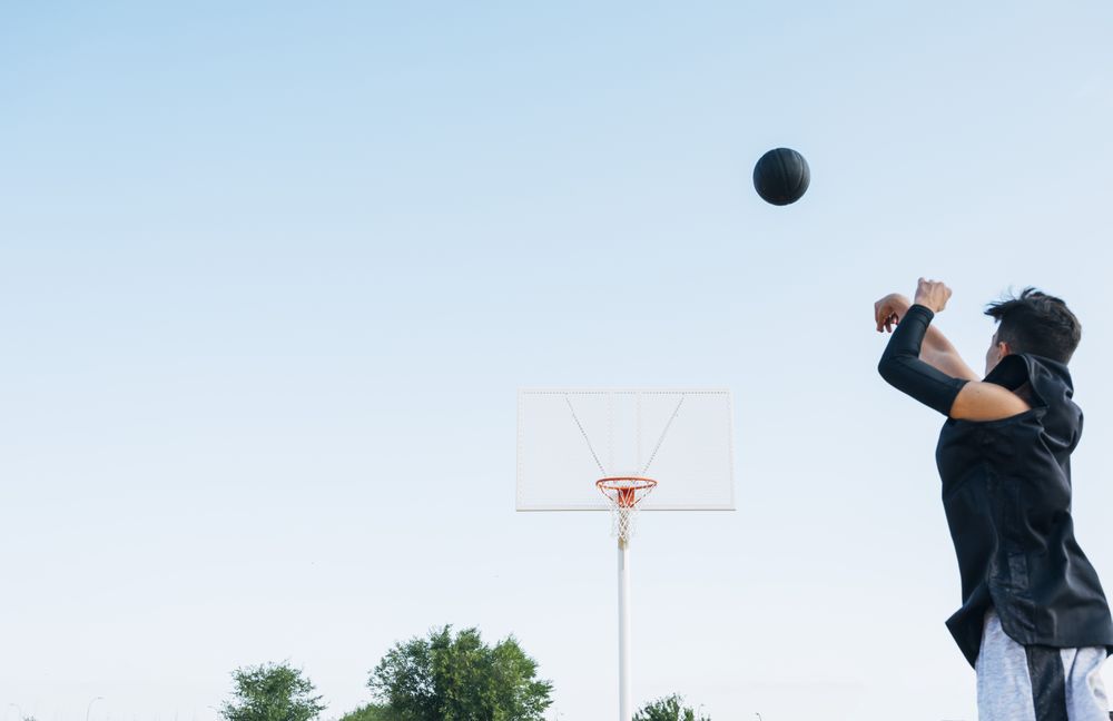 Young man playing on yellow basketball court outdoor.