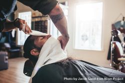 Barber applying warm towel to man’s face 411Vg4
