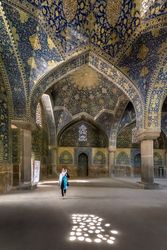 Woman standing in mosque with colorful tiles on dome
