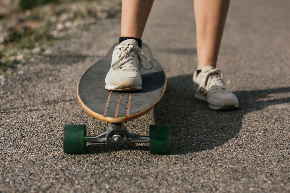 Anonymous woman riding longboard on asphalt road