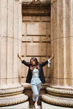 woman leaning on pavement between tall massive columns and looking down in San Francisco