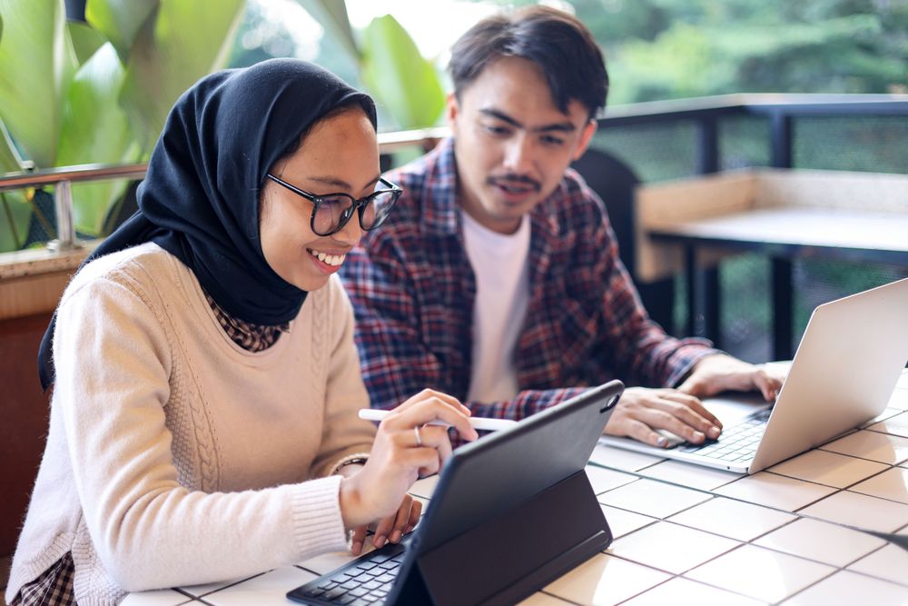 Asian Hijab Female Working at the Cafe with Her Colleague