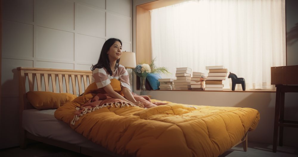 Korean Woman Waking up in the Morning, Doing some Stretching, Welcoming a Sunny Day With Sun Shining Through her Window.