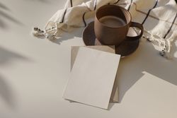Cup of coffee and checkered plaid on table with blank card
