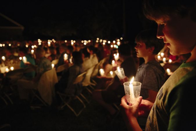 People holding lit candles at a gathering during nighttime