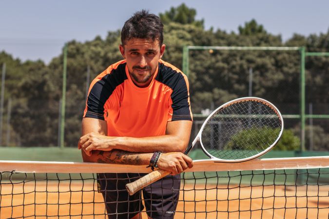 Man in sportswear playing tennis on a dirt tennis court