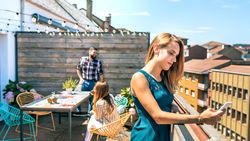 Young woman with green dress looking mobile on rooftop