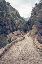 Cloudy sky over narrow stone path in mountainous valley
