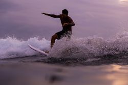 Man on surf board on waving water at sunset