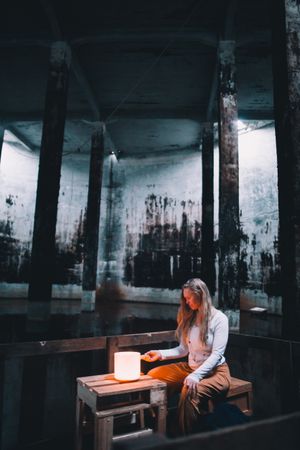 Woman with praying hands near lamp on bench in building
