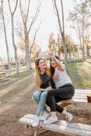 Smiling women taking selfie in park