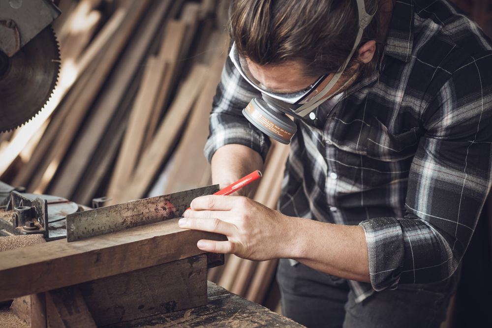 Male carpenter measuring wood with ruler and pencil