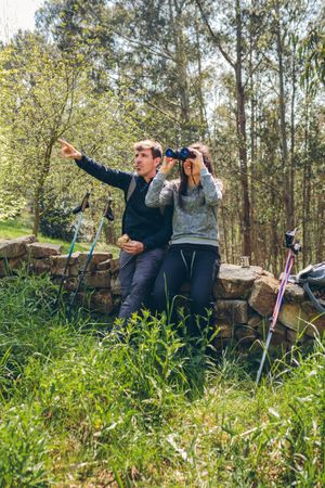 Couple doing trekking looking with binoculars