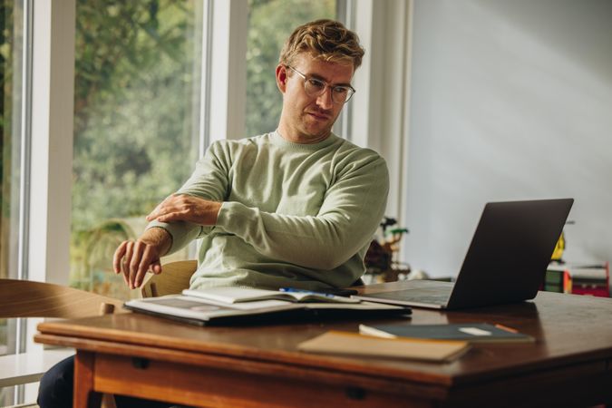 Man rolling up sleeves of his t-shirt while working from home