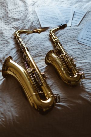 Saxophones and printed musics on bed