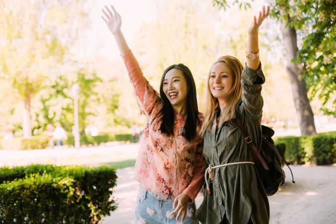 Cheerful multiethnic women greeting friend in park