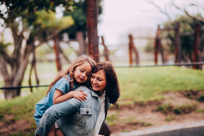 Mother gives her daughter a playful piggy back ride outside