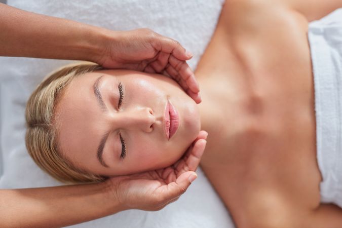 Blonde woman with eyes closed during facial treatment