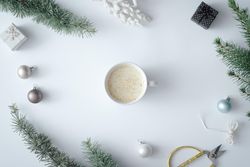 Coffee cup with winter branches and decorations on pastel grey background