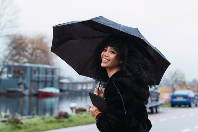 Smiling woman with umbrella on street