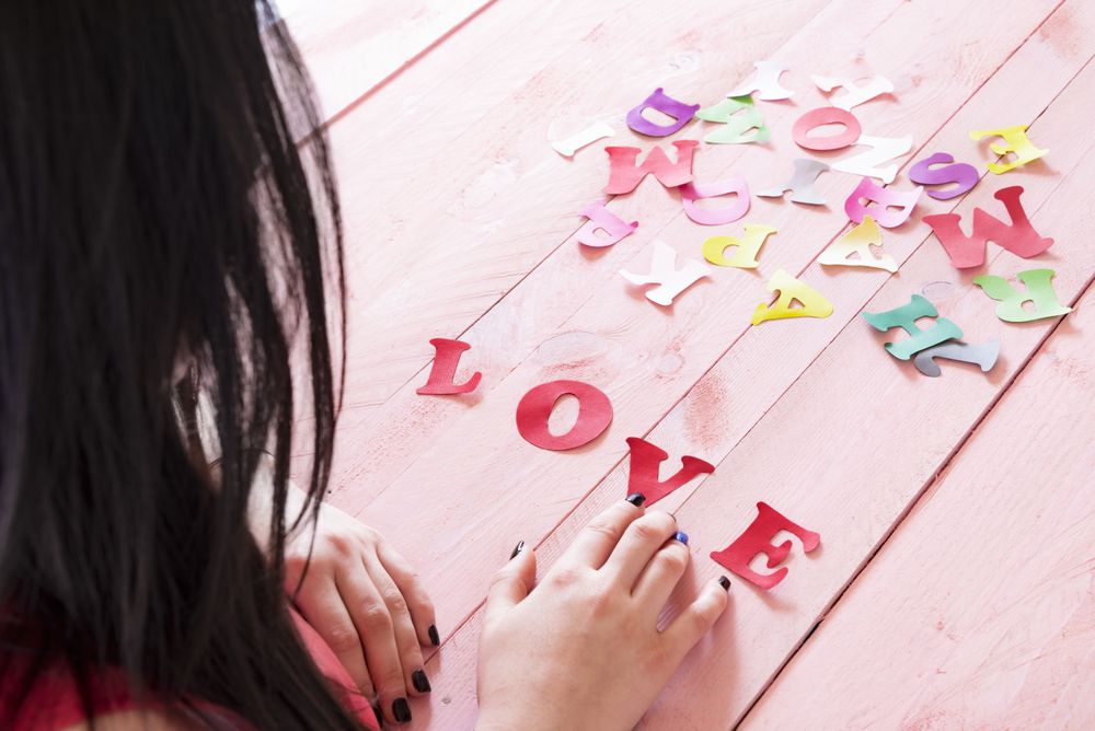 Shot of the back of woman touching paper letters and the word love