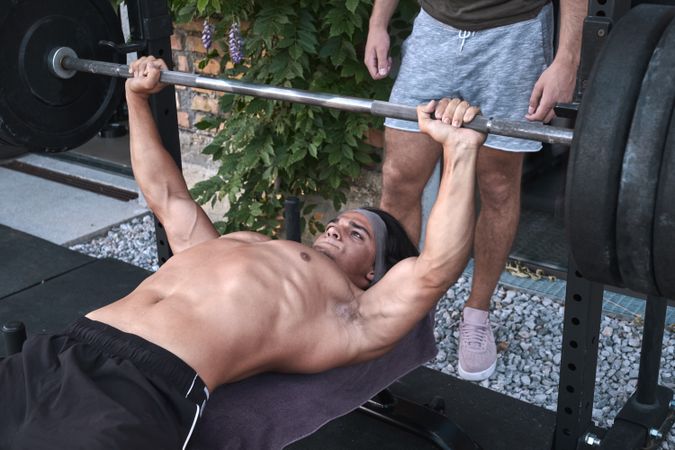 man lifting barbell with trainer