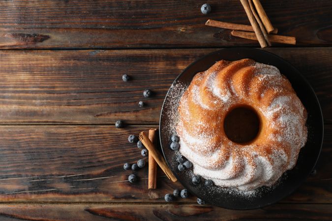 Cake with powder sugar and blueberry on wooden background, top view