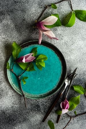 Floral scene with magnolia blooming on teal plate