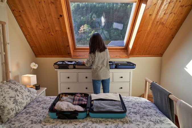 Anonymous woman packing suitcases in bedroom
