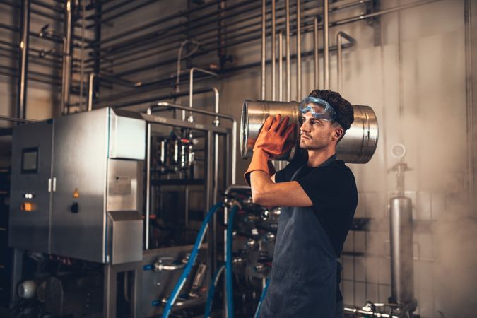 Male worker carrying craft beer keg to storage unit