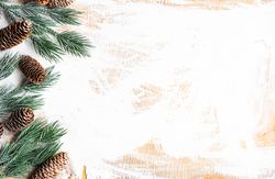 Christmas card concept of branch and pine cones on rustic table