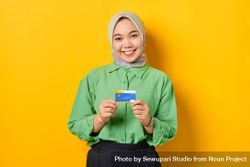 Kind Muslim woman in headscarf and green blouse holding credit card 47dgOb