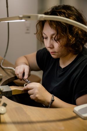 Focused adult craftswoman working in jewelry atelier