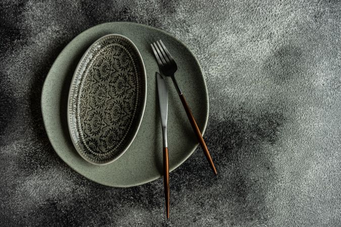 Grey plate, on grey background with cutlery