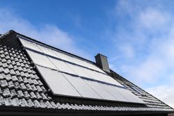 Solar panels with snow on it producing clean energy on a roof of a residential house.