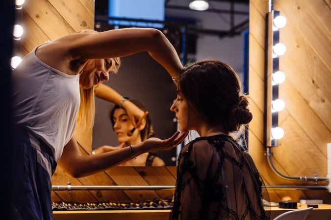 Makeup artist doing makeup for young female artist