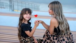 Mom and little daughter with red heart shaped lollipop outdoor