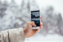 Hand taking photo of wintry scene with phone