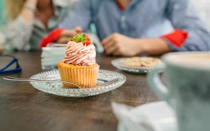 Cupcake with couple holding hands in background