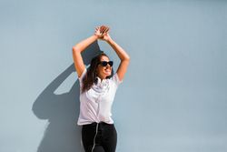 Cheerful casual woman in sunglasses standing on city street