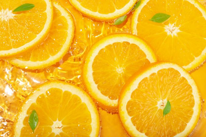 Top view of orange slices with leaves soaking in fresh water